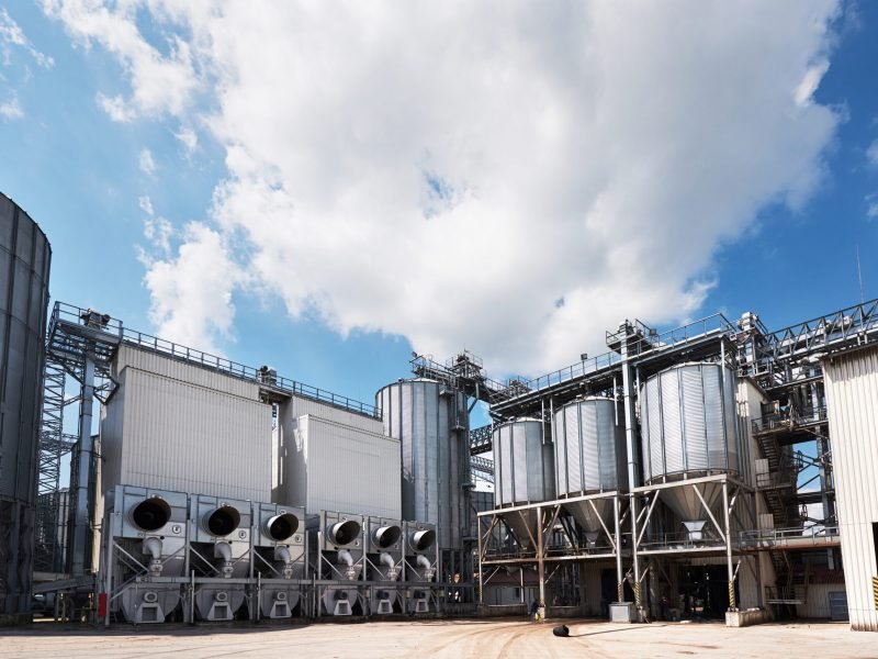 Agricultural Silos. Building Exterior. Storage and drying of grains, wheat, corn, soy, sunflower against the blue sky with white clouds.